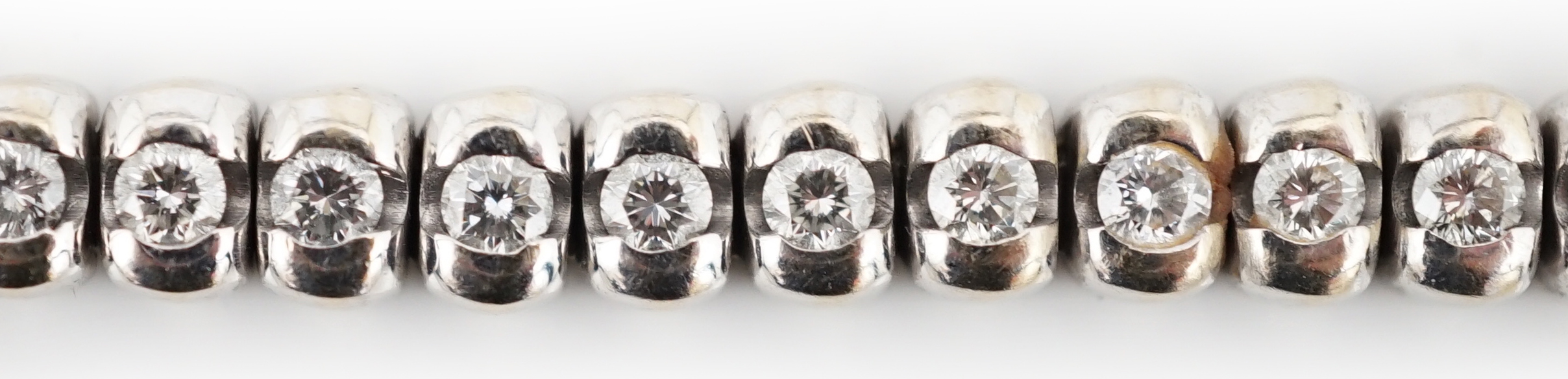 A modern 18ct white gold and collet set forty seven stone round brilliant cut diamond set line bracelet